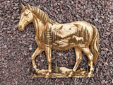3D illusion double exposure of a horse with a mountain scene inner image, laser burned into wood, shown laying on gravel as a backdrop